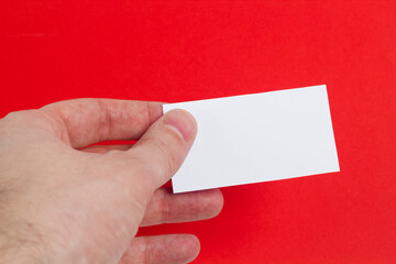 White blank business card in hand on red background