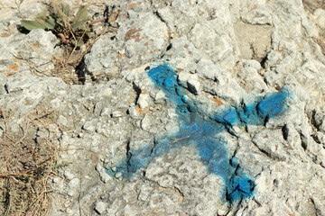 Blue cross as a mark on the rock surface, treasure hunt concept