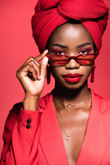 african american woman in stylish outfit, sunglasses and turban isolated on red