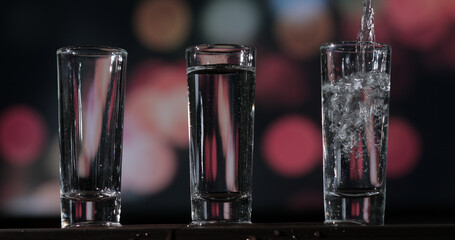 Bartender pouring up tequila into three shots glasses.