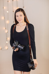 young brunette woman dressed in black with 2 cameras on a leather strap