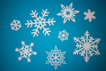 Fototapeta na wymiar White paper snowflakes on light blue background