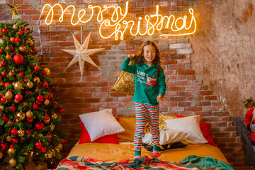little girl Asian girl in her pyjamas in the bedroom messing around on the cushions, Christmas, new...