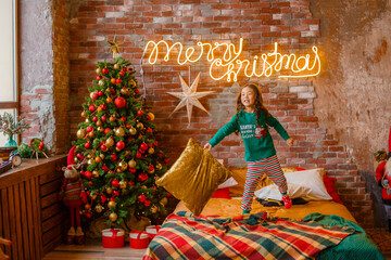 little girl Asian girl in her pyjamas in the bedroom messing around on the cushions, Christmas, new...