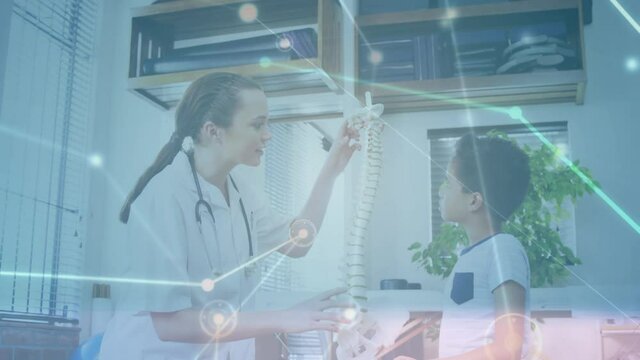 Digital animation of glowing network of connections moving against female doctor showing human spine
