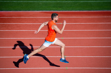 athletic muscular male running on racetrack at outdoor stadium, aim