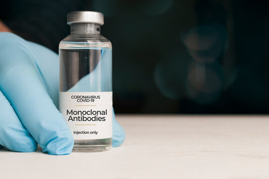 Doctor Hold A Vial Of Monoclonal Antibodies, A New Treatment For Coronavirus Covid-19, On A White Table