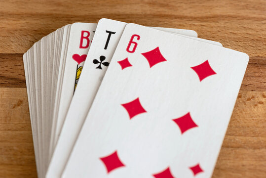Paper playing cards for playing poker on the background of a wooden brown board.