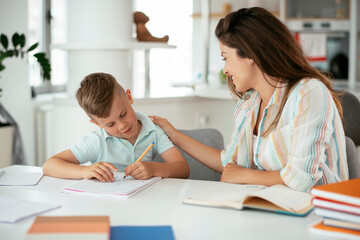 Obraz premium Mother helping her son with homework at home. Little boy learning at home...