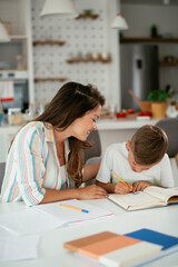 Mother helping her son with homework at home. Little boy learning at home...