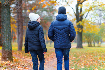 teen girl and boy walking through the park and enjoys autumn, beautiful nature with yellow leaves