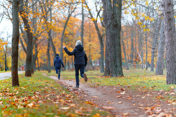 Fototapeta premium teen girl and boy running through the park and enjoys autumn, beautiful nature with yellow leaves