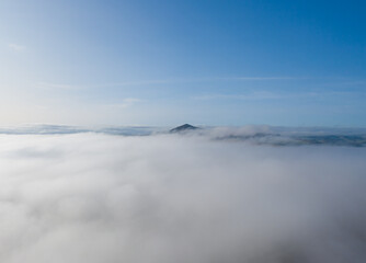 Mountain sitting above the clouds with blue skies and thick fog