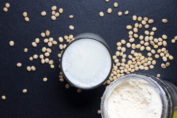 soy milk in a glass with soybeans seeds in the background