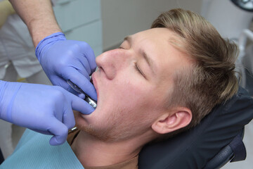 The dentist made an impression of the patient's teeth. A young man at a doctor's appointment. Hands in protective gloves. The concept of beauty or health.
