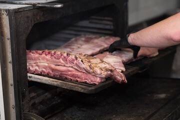 A chef in a very nice pub smokes pork ribs in a large oven