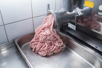 In the kitchen, creating minced pork meat through a meat grinder