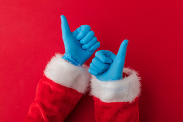 Santa hands wearing blue PPE protective gloves making thumbs up sign