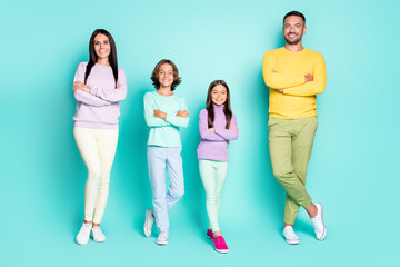 Fototapeta premium Photo portrait of full family with small kids all with folded arms isolated on vivid turquoise colored background