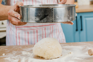 Making dough with men's hands on a wooden table.