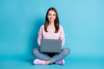 Naklejka premium Full length photo of pretty lovely student girl sitting floor crossed legs hold laptop freelancing copywriting chilling wear violet pullover sneakers denim isolated blue color background