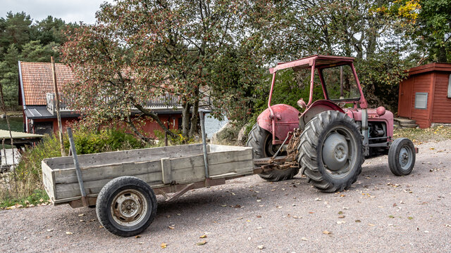 Retro red old tractor with a chariot along the road