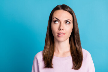 Fototapeta premium Closeup photo of attractive lady deep thinking look up side empty space dilemma question bite lips not sure about answer wear casual pink sweatshirt isolated blue color background