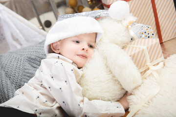 Portrait of a cute little boy child wearing a silver color Christmas hat laying on gift boxes.Merry Christmas and Happy Holidays!