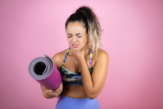 Young beautiful woman wearing sportswear and holding a splinter over isolated pink background touching painful neck, sore throat for flu, clod and infection