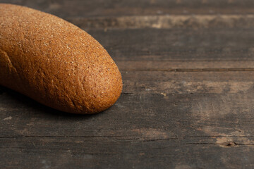 Freshly baked traditional black bread on a wooden table. brown coarse bread made from shenitsa, barley, rye flour.