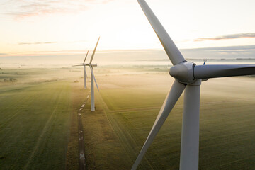 Aerial view of three wind turbines in the early morning fog at sunrise in the English countryside - Powered by Adobe