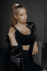 Pretty minimalist portrait of blonde female model on grey background. stylish clothing, black classic style concept