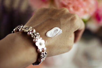 White moisturizer on a woman's hand. Blurred background.