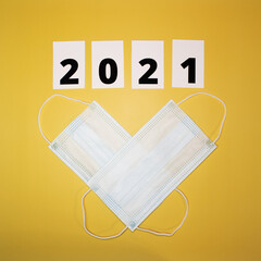 Medical mask, numbers 2021 on a yellow background. Flat lay composition on the theme of new year and christmas. Medical design