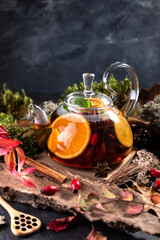 Fototapeta na wymiar Fruit tea. Seasonal winter autumn hot drink. Citrus and berry tea with lemon, oranges in glass teapot on dark table