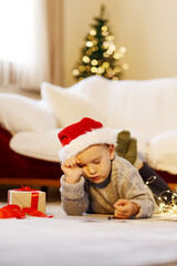 Cute boy in a red cap fell asleep writing letters to Santa. Christmas concept.