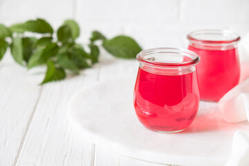 Sweet dessert jelly pudding with raspberries berries in glass jar on white background