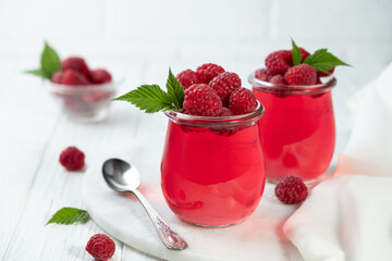 Sweet dessert jelly pudding with raspberries berries in glass jar on white background