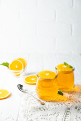 Sweet dessert jelly pudding with orange citrus in glass jar on white background