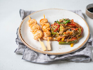 Prawn Skewer and vegetables stir fry on white plate.