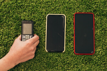 The Human Hand Picks an Old Phone That Lies Near New Smartphones