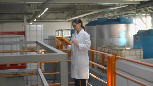 Technologist expert using tablet computer in chemical factory production line.