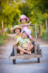 Three Asian girls sitting on a wooden cart smile and laugh happily.