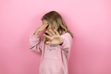 Young beautiful child girl standing over isolated pink background covering eyes with hands and doing stop gesture with sad and fear expression. Embarrassed and negative concept.