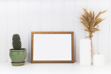 Image of mockup scene with empty wooden frame. Cactus, candles and deadwood