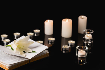 Fototapeta na wymiar lily, candles and holy bible on black , funeral concept