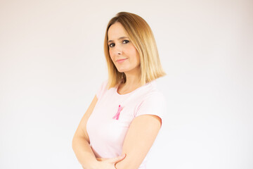 Women against breast cancer. Beautiful woman wearing casual t-shirt with a pink ribbon on her chest and smiling, on white background