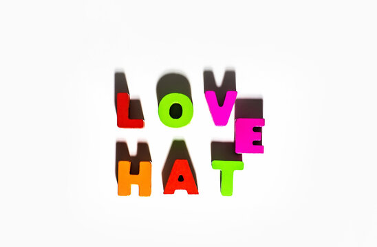Love Hate words spelling by wooden colorful letters with common E and shadows at isolated white background, opposite contrast feelings 