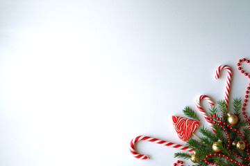 Flat lay. Christmas and New Year theme. Christmas tree branches, golden balls, candy canes, red beads. White background.