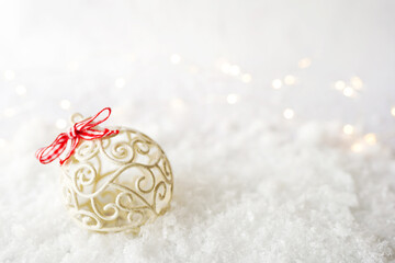golden christmas ball decoration lying on the snow, copy space